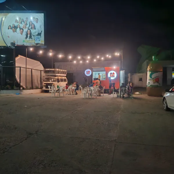 Vista noturna do point com varal de luzes e mesas ao ar livre