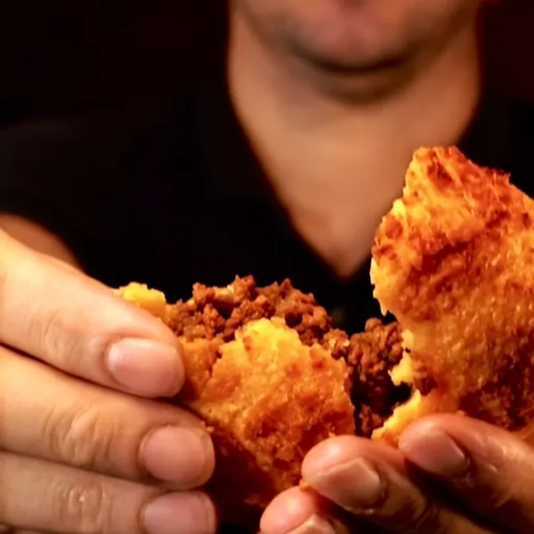 Coxinha crocante sendo partida ao meio